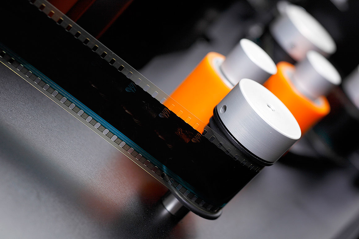 Film passing through a series of rollers prior to scanning.